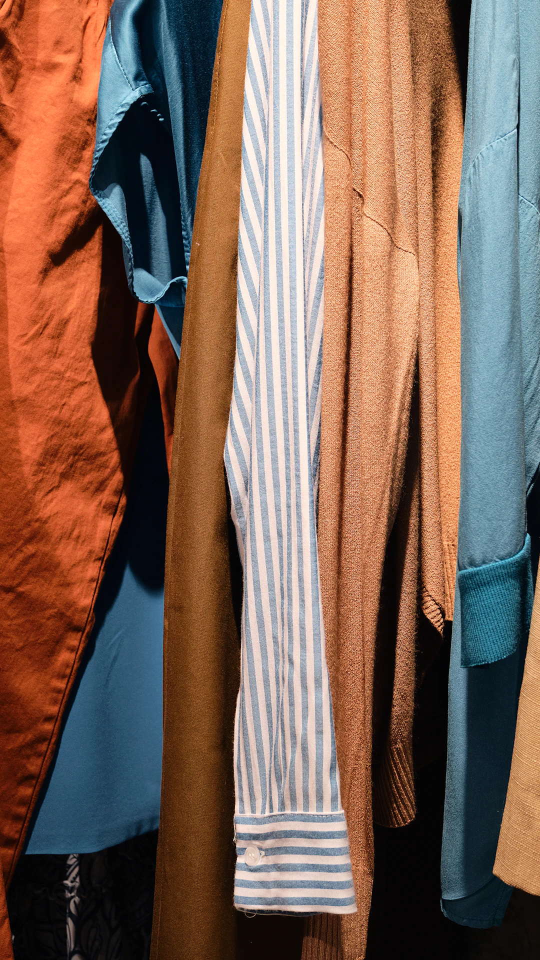 a bunch of different colored shirts hanging on a rack