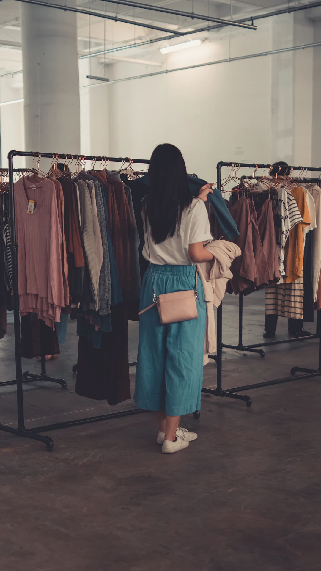 a woman standing in front of a rack of clothes