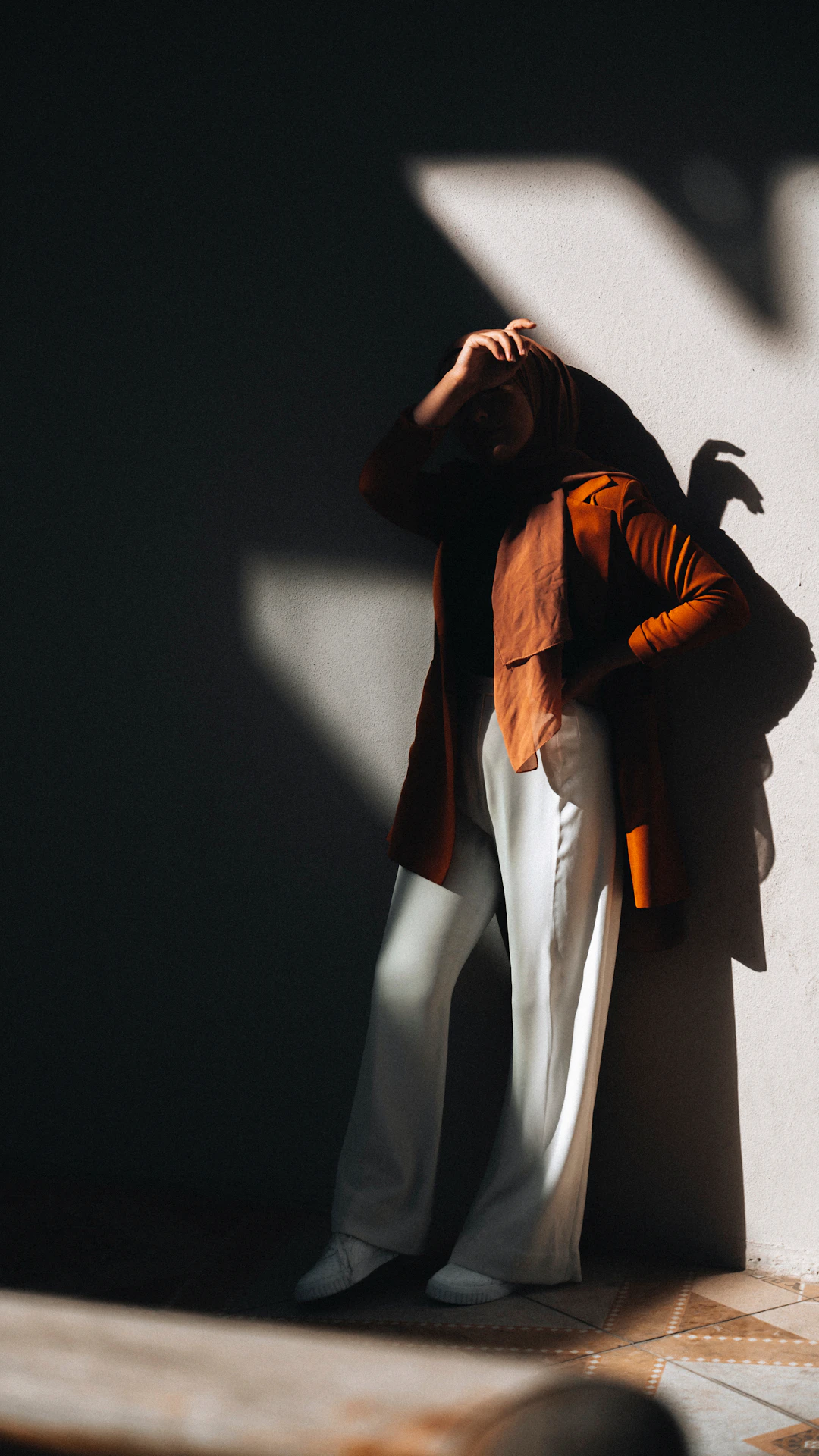 a woman standing against a wall with her hands on her head