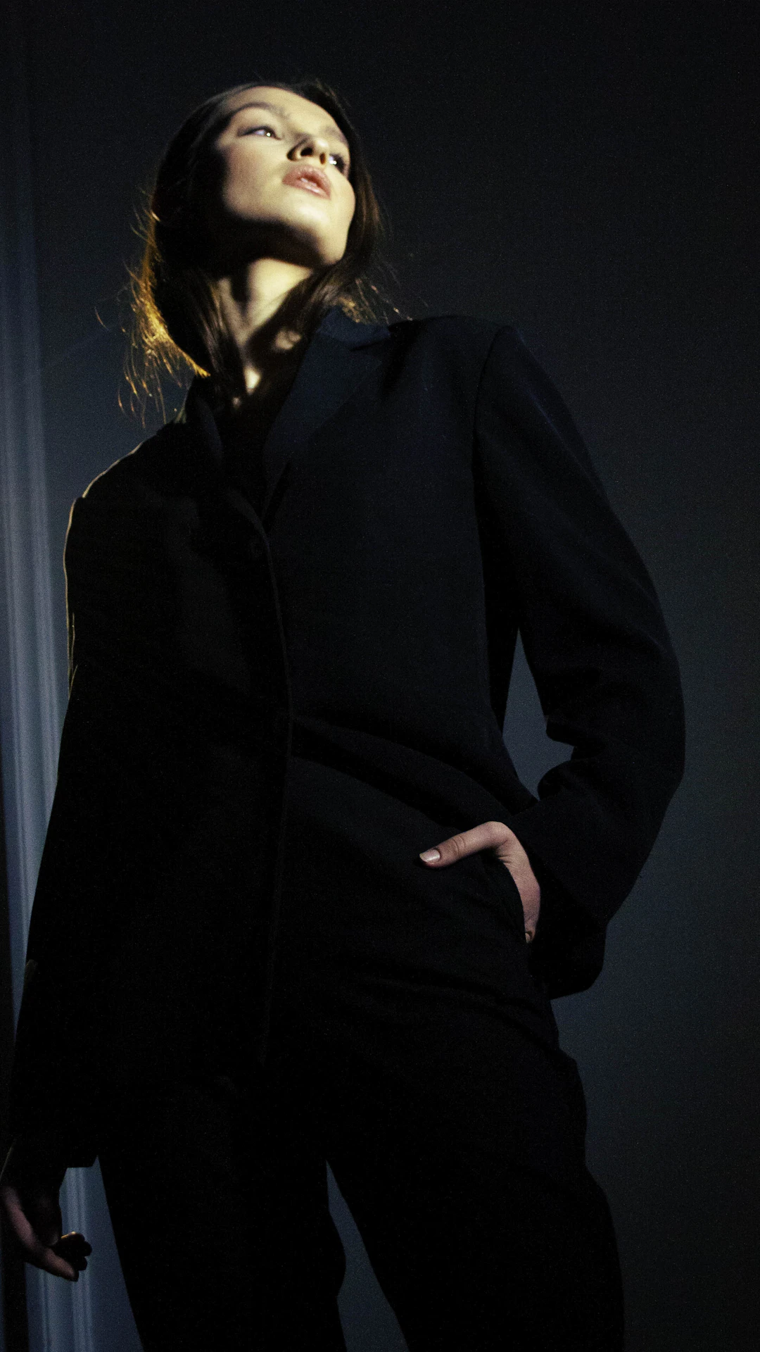 a woman standing in a dark room with her eyes closed