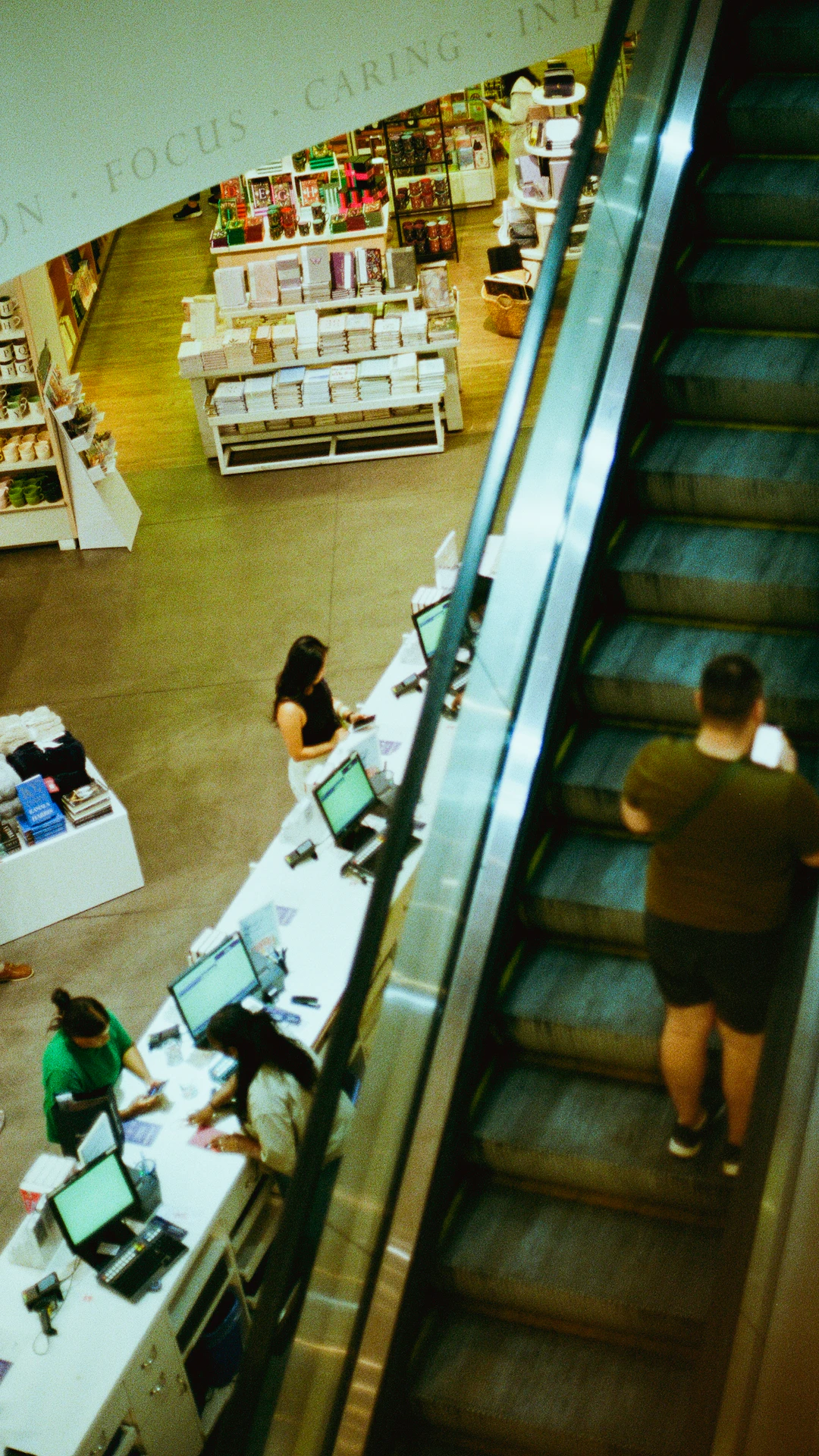 People on escalator in a brightly lit store.