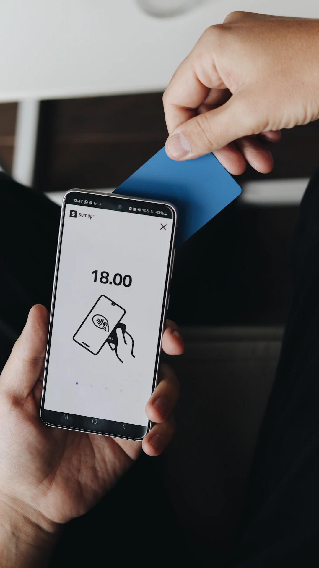 A person holding a cell phone and a credit card