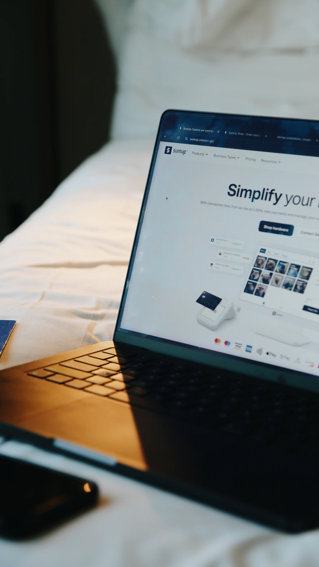 Laptop, phone, and card on a bed.