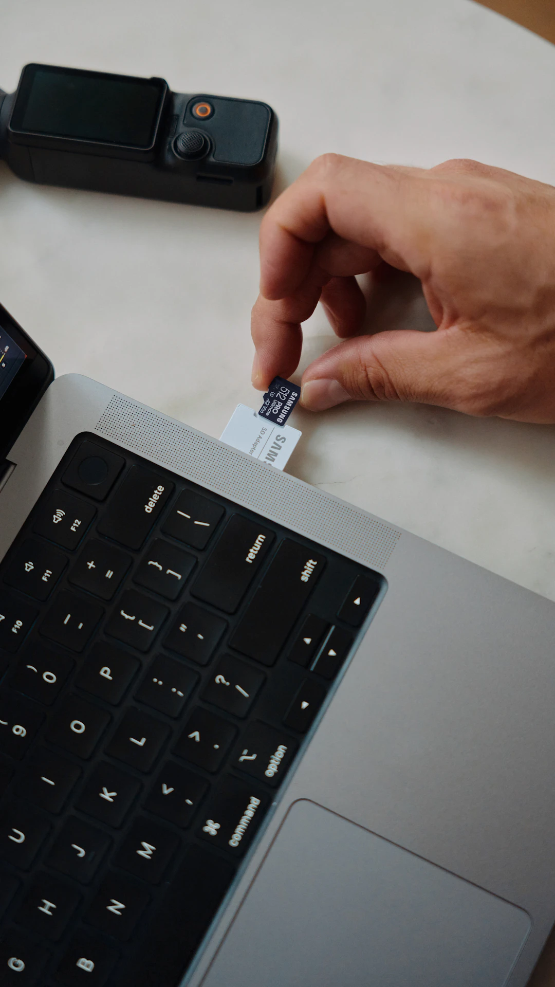 A person's hands holding a card over a laptop
